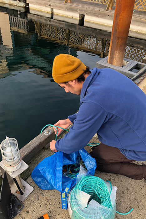 Man on dock with NIC prototype for oyster growing