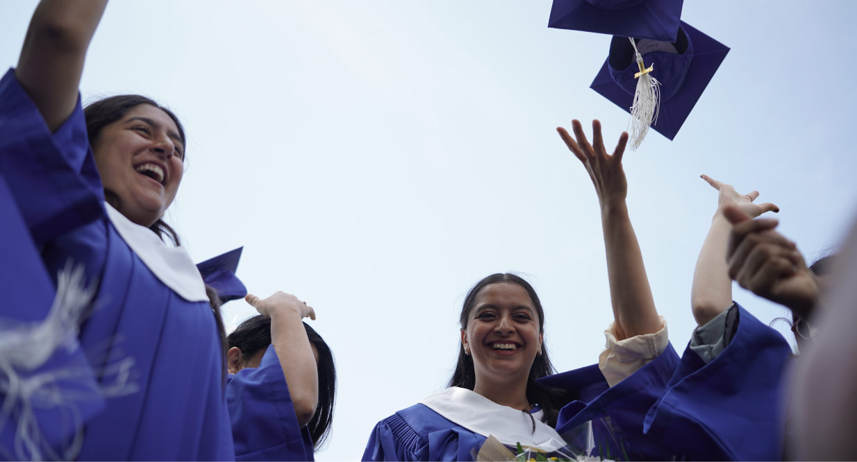 A group of NIC graduates in regalia gathered together laughing