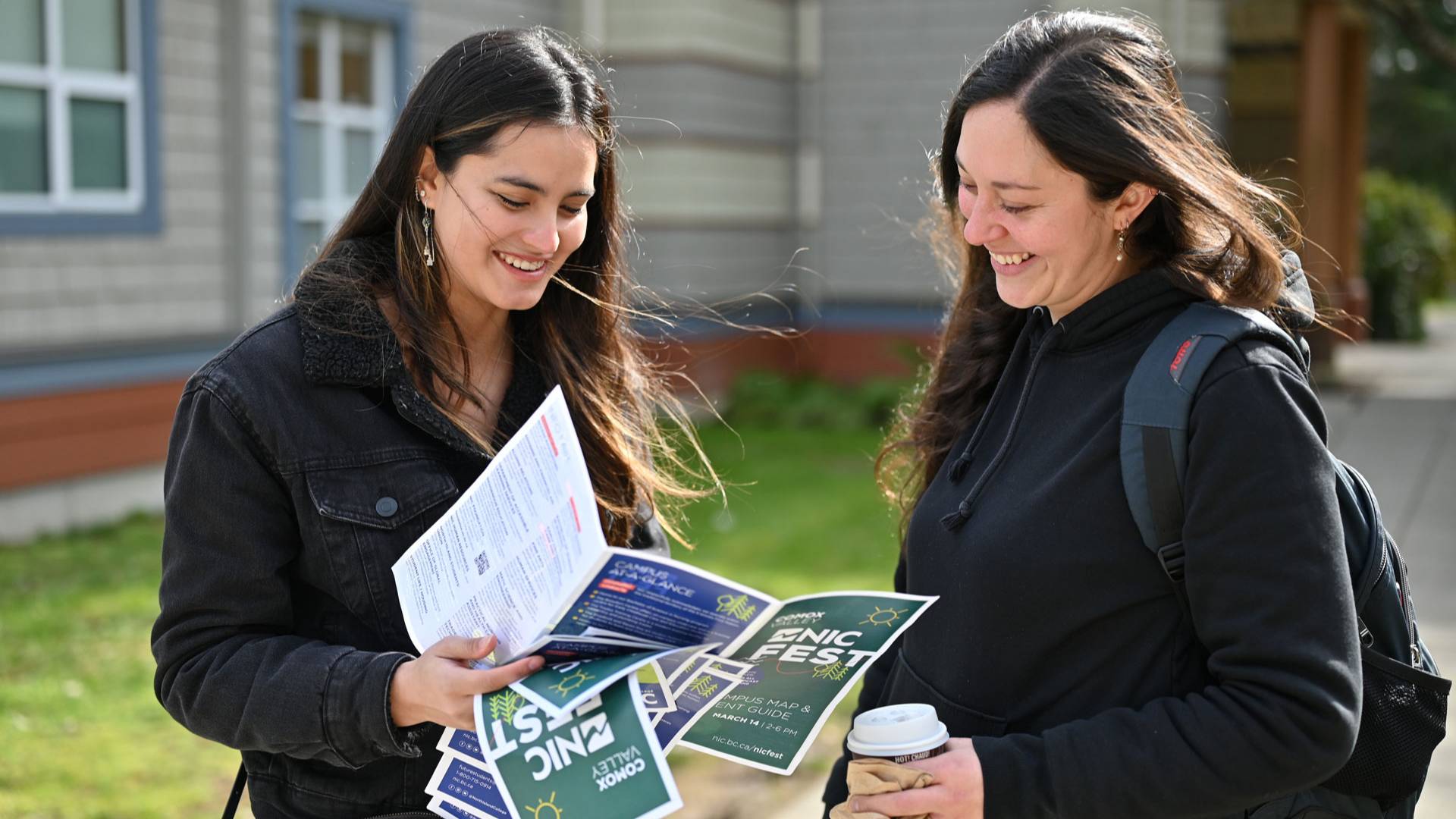 NIC Fest attendees review the event guide in the sunshine outside the Comox Valley campus