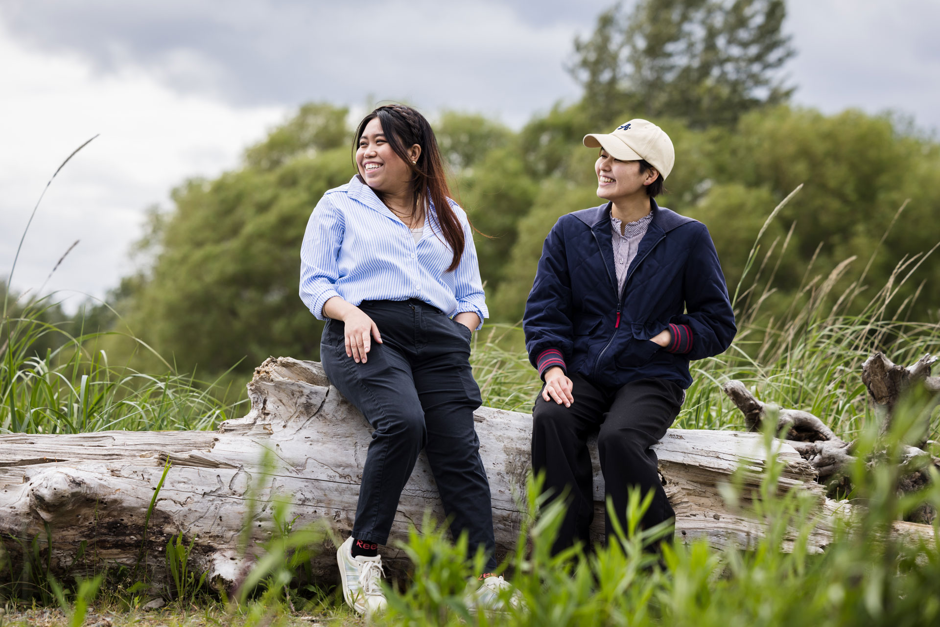 Students sitting and talking on a driftwood log at a local beach