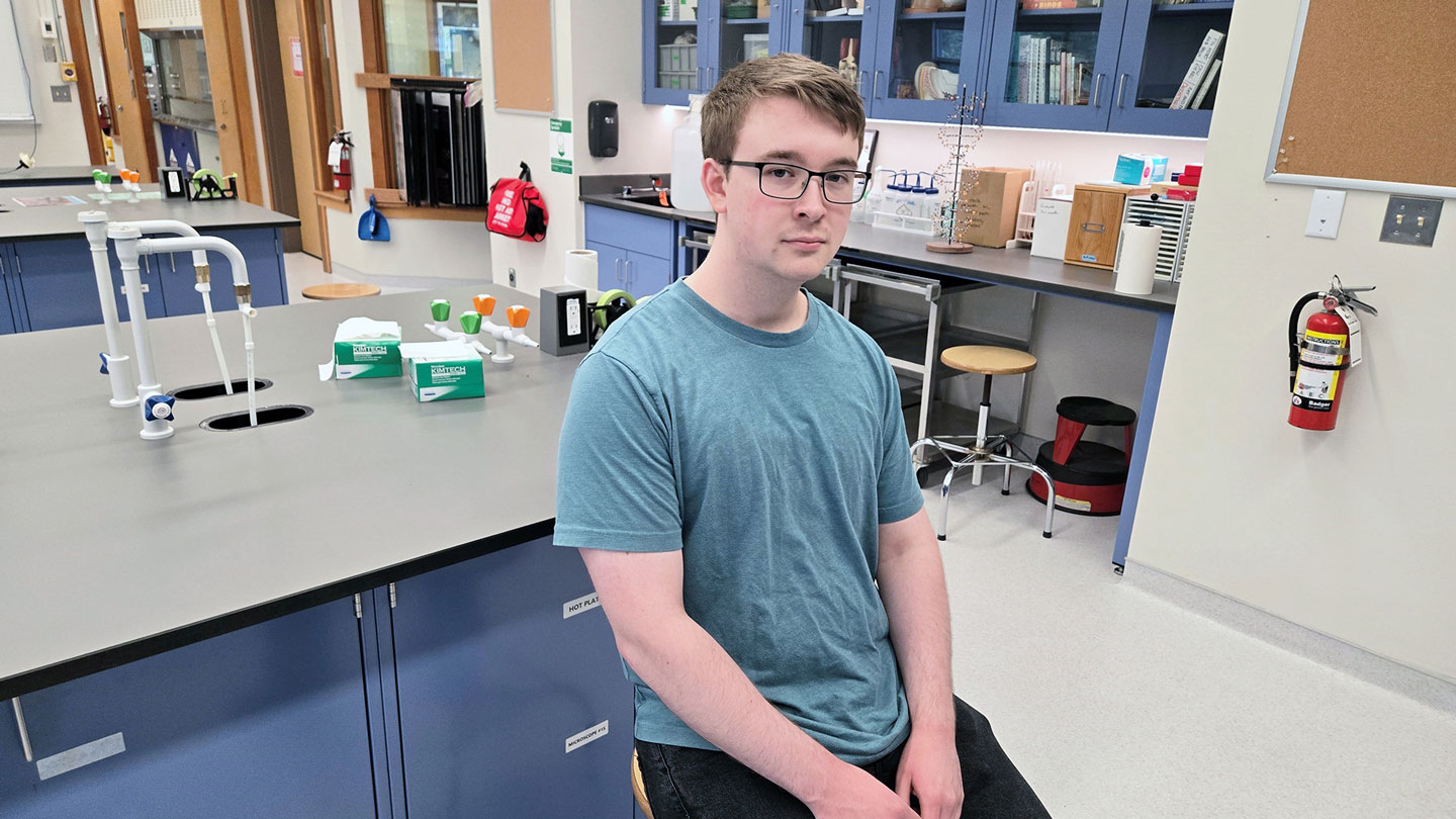 A college student sits inside a lab.