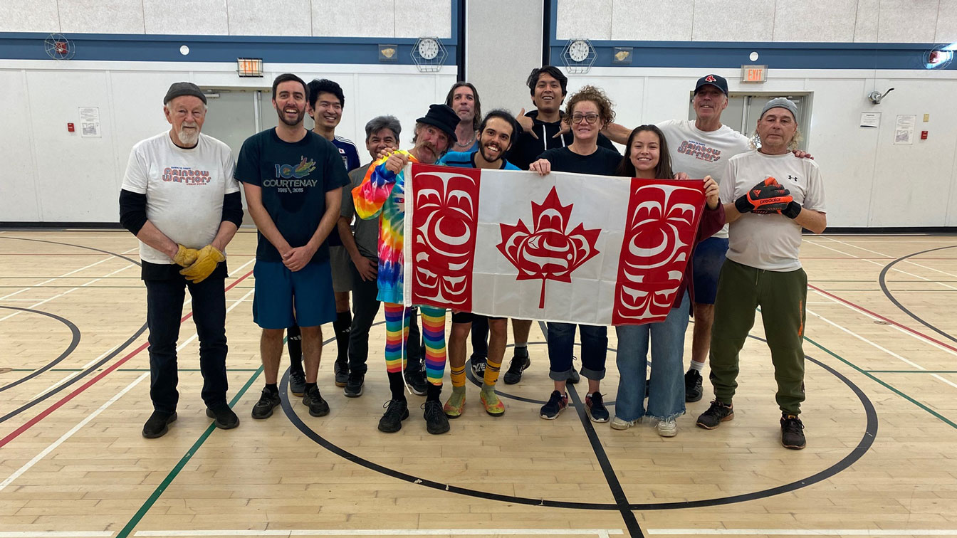 Soccer players posing in gym with flag