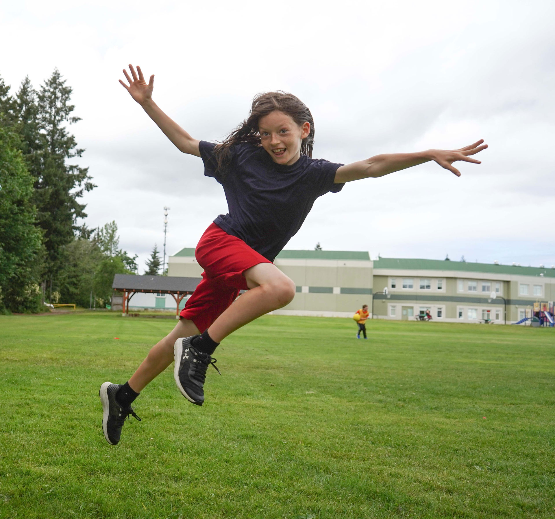 Youth Academy sports and STEM camp participant jumps on a soccer field