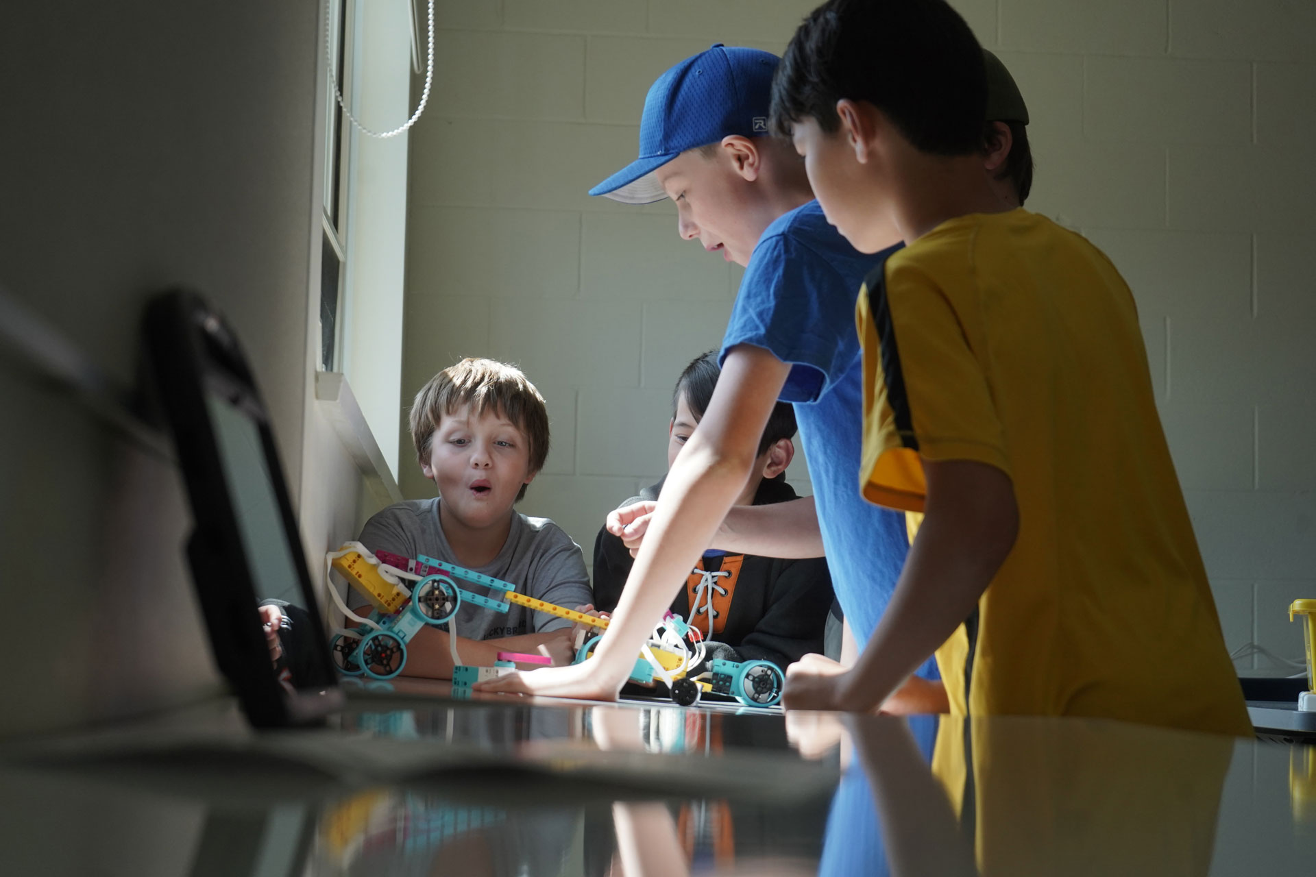 Three Youth Academy Robot Camp participants working on a bot