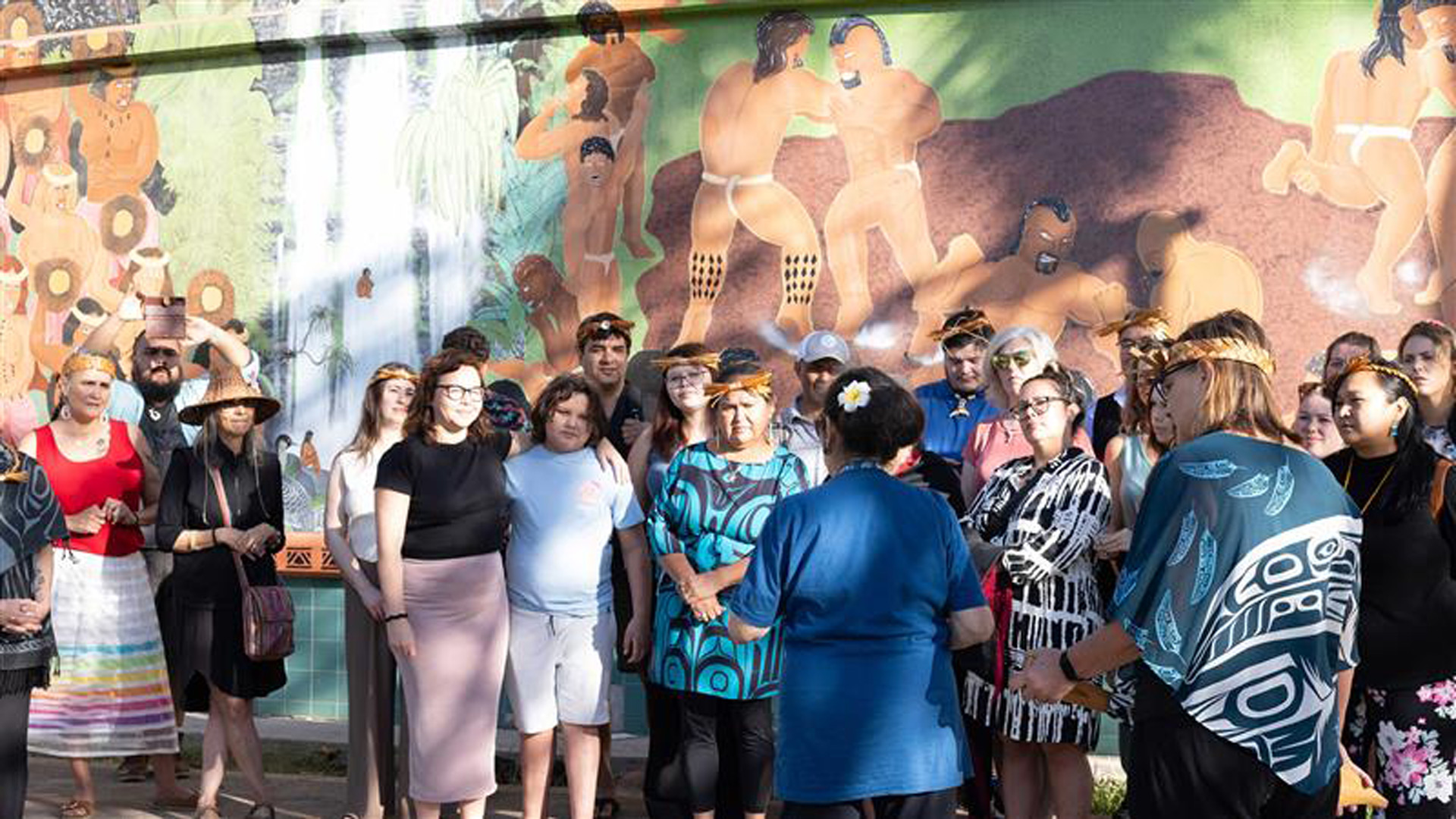 A group stands in front of traditional mural